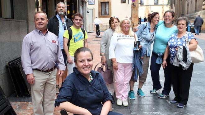 Natalia García, con un grupo de turistas detrás, posa ante El Ovetense, si su ansiada terraza. 