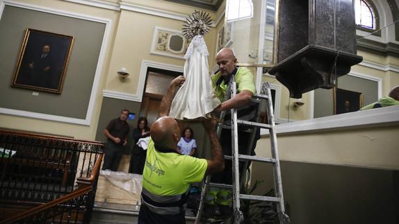 La virgen es trasladada por unos operarios municipales.