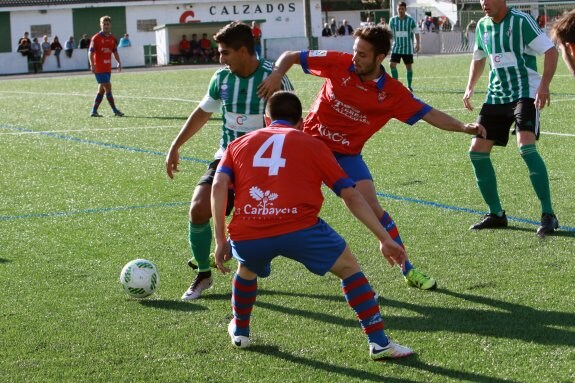 Un jugador local, rodeado de dos rivales gijoneses. 