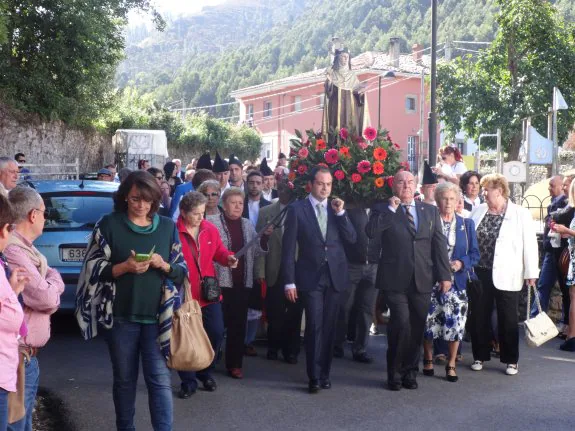 Las andas con la imagen de Santa Teresa, arropada por los devotos, ayer en las calles de Nueva. 