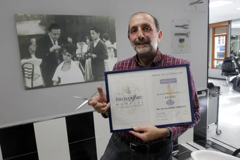 Antonio Gorriz, en su peluquería de la calle Uría, con el diploma que acredita su última premio. 