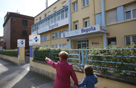 Una mujer y una niña pasan por delante del hospital. 