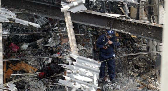 Un agente de la Policía Científica entre un amasijo de escombros en el local incendiado. 