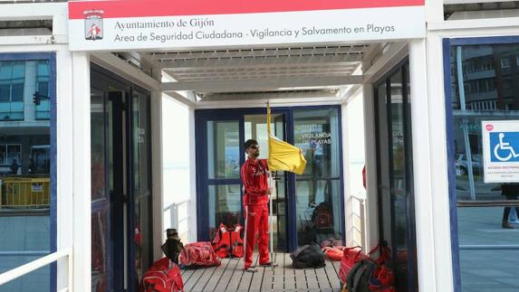 Un miembro del equipo de salvamento coloca la bandera amarilla con la que se estrenó el servicio este año.