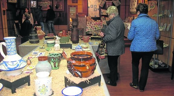 Un par de visitantes observan  los trabajos del taller de cerámica. 