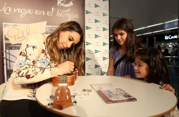 Paula Rojo firma sobre un ukelele a una de las pequeñas que acudió a la presentación. 