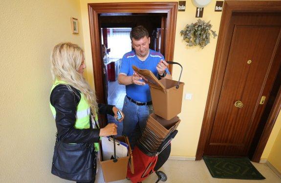 Silvia Peralta entrega el cubo marrón a Diego Montero en la campaña puerta a puerta. 