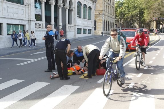 Policías locales y viandantes asisten al ciclista herido, frente a la Pescadería Municipal. 