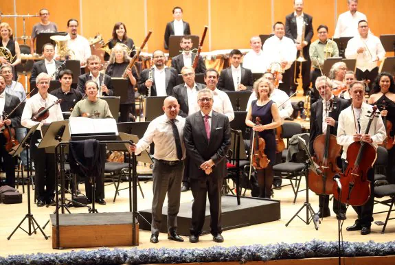 El director de la orquesta, Roberto Beltrán, y el financiero asturmexicano Juan Antonio García posan con la Orquesta Sinfónica de la Universidad de Guanajuato en el ensayo general del concierto. 