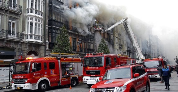 Los bomberos, durante el incendio del número 58 de la calle Uría el 7 de abril de 2016. 