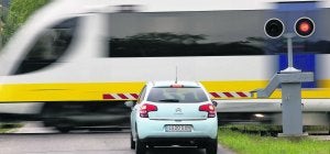 Un vehículo interrumpe la marcha para ceder el paso a un tren de Feve en un paso a nivel de Nueva de Llanes. ::                             JORGE PETEIRO