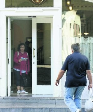 Un turista se dirige hacia un hotel gijonés mientras otra se dispone a salir con un plano. ::                             PALOMA UCHA