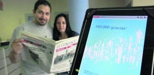 Dos lectores con un ejemplar del diario en papel y, en primer término, una tableta con la versión digital. ::
JORGE PETEIRO