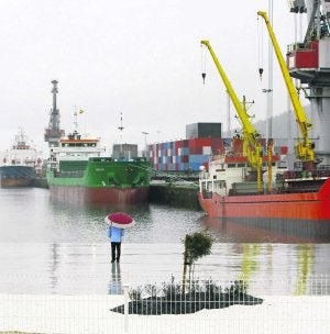 Una persona observa bajo la lluvia la actividad en los muelles de la margen derecha. ::                             MARIETA