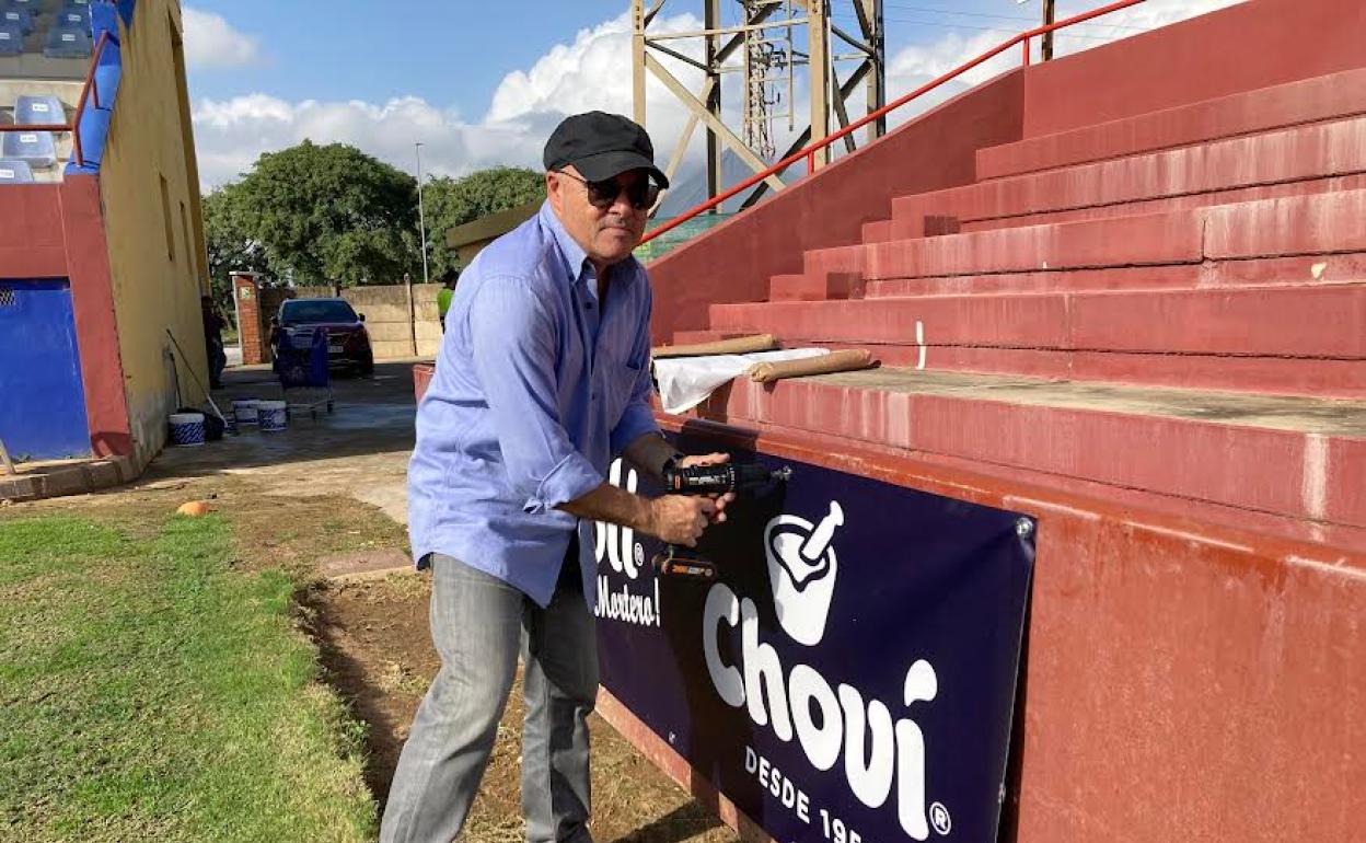 Juan Antonio Sanjuán, presidente del Alzira, coloca un cartel publicitario.