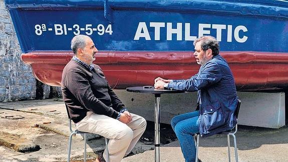 Juan Carlos Latxaga conversa con el periodista de EL CORREO, Jon Agiriano, junto a la gabarra del Athletic.