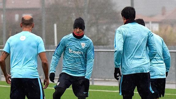 Los jugadores del Athletic, protegidos contra el frío y la lluvia que azotan Bizkaia, durante el entrenamiento de ayer en Lezama.