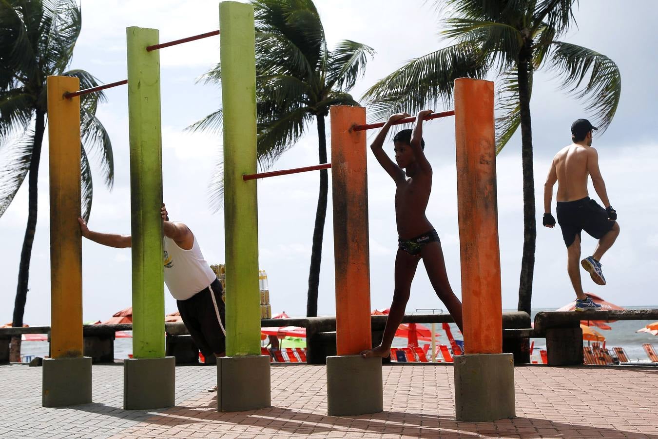 Un niño y dos hombres hacen ejercicios en los alrededores de la playa en la ciudad de Recife