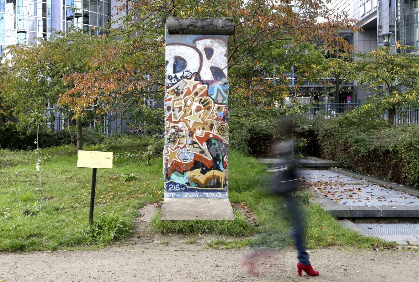 Una mujer camina por delante de una parte del Muro de Berlín, en un parque en el exterior del Parlamento Europeo, en Bruselas.