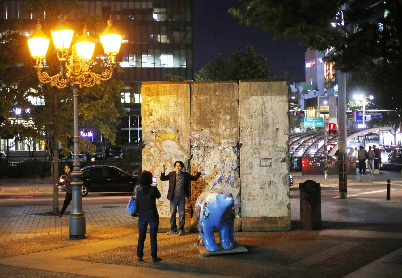 Una mujer toma una fotografía de su marido frente a una parte del Muro de Berlín instalado en una plaza de Seúl.