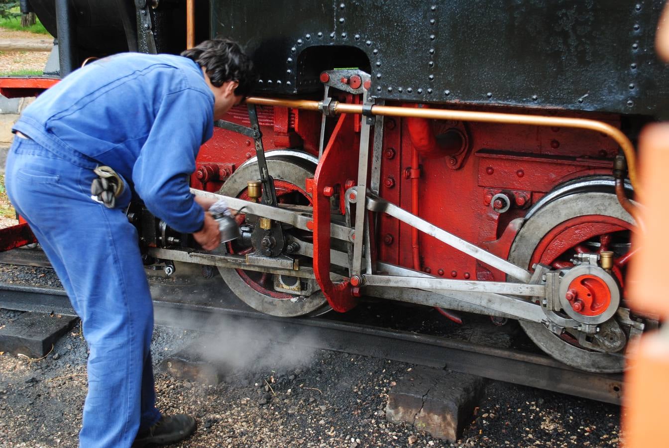 Un operario engrasa la locomotora de vapor.