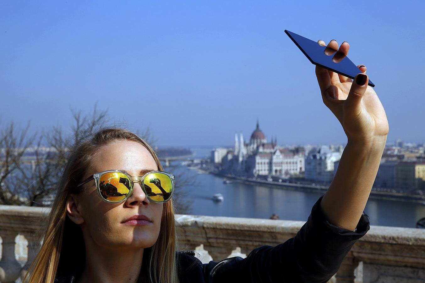 Eclipse solar 2015: Así se ha vivido. BUDAPEST (HUNGRÍA). Una joven mira al cielo a través de unas gafas y de un móvil para observar el eclipse parcial de sol con el que se despide el invierno.