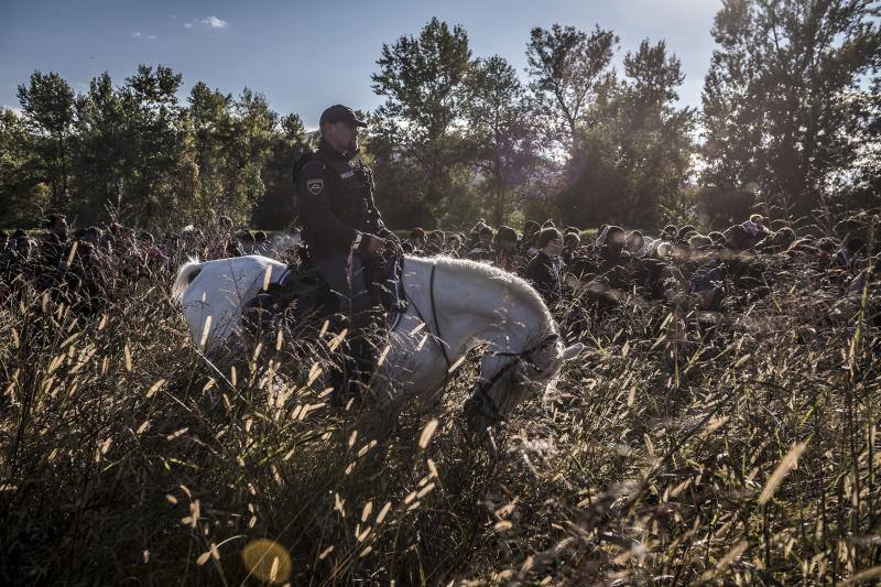 Un grupo de migrantes camina encima de un dique mientras la policía antidisturbios eslovena los acompaña al campo de registro de Dobova (Eslovenia). Serie ganadora de Noticias de Actualidad.