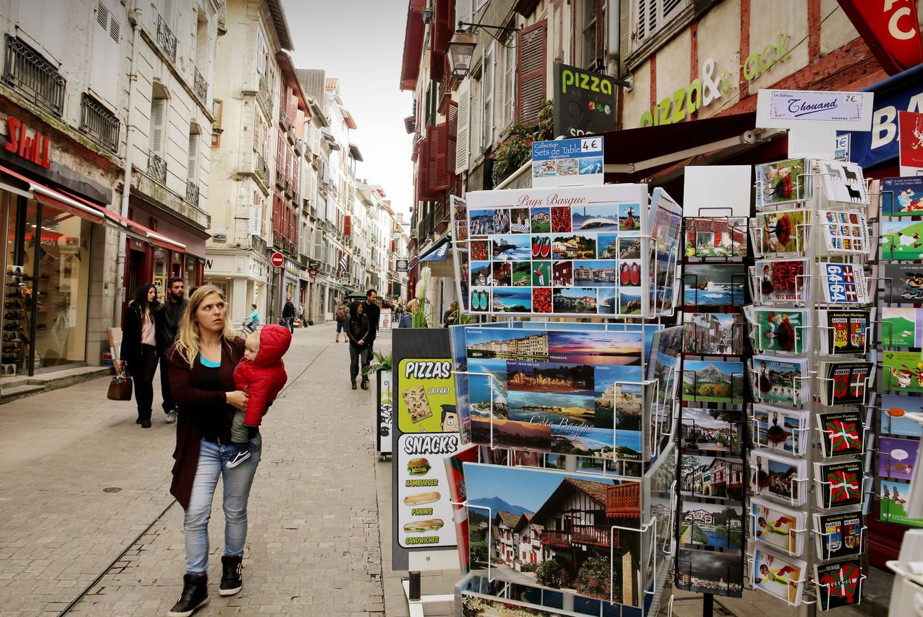 Turistas y vecinos pasean por una calle típica de Bayona.