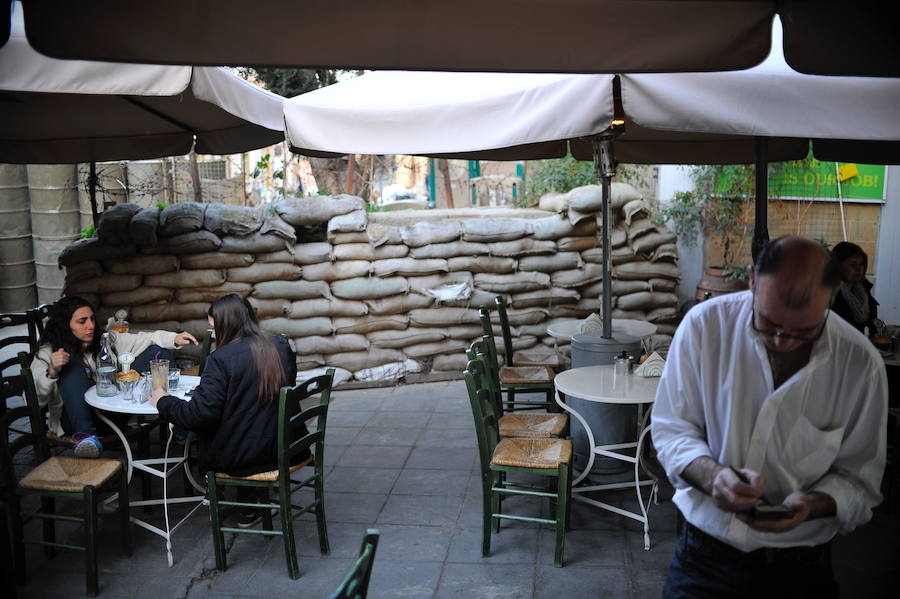 Unas turistas, en una cafetería situada junto a unos fajos que hacen de muro.