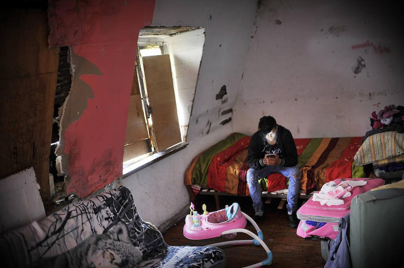 Un joven mira el móvil en una desconchada habitación del edificio que será derribado.