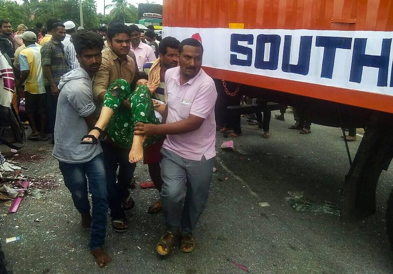 Un hombre indio ayuda a llevar a una mujer herida a ambulancia.