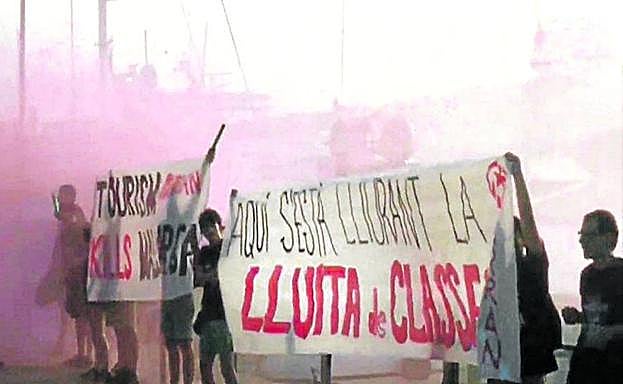 Imagen principal - ‘Escrache’. Activistas de Arran se manifiestan con pancartas y botes de humo ante los barcos y restaurantes del puerto de Palma. Debajo, pintadas contra los turistas en la capital balear. 