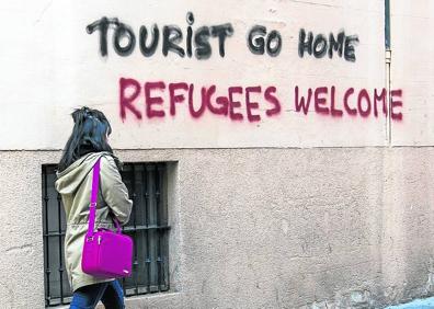 Imagen secundaria 1 - ‘Escrache’. Activistas de Arran se manifiestan con pancartas y botes de humo ante los barcos y restaurantes del puerto de Palma. Debajo, pintadas contra los turistas en la capital balear. 