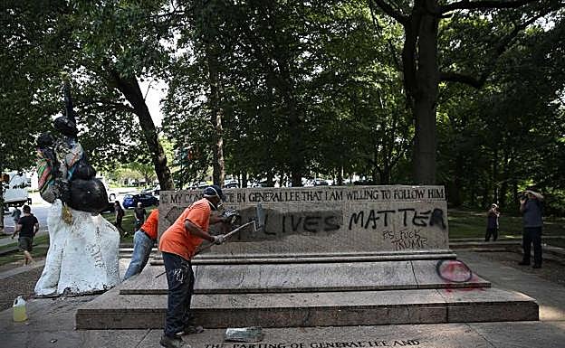 Empleados públicos borran los escritos en una de las estatuas retiradas en Baltimore.