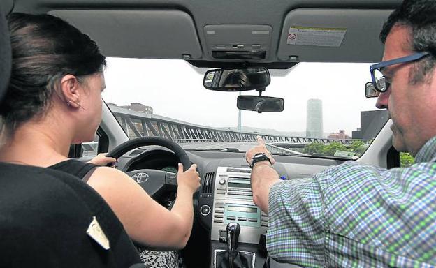 Un profesor de autoescuela enseña a conducir a una joven en Bilbao.