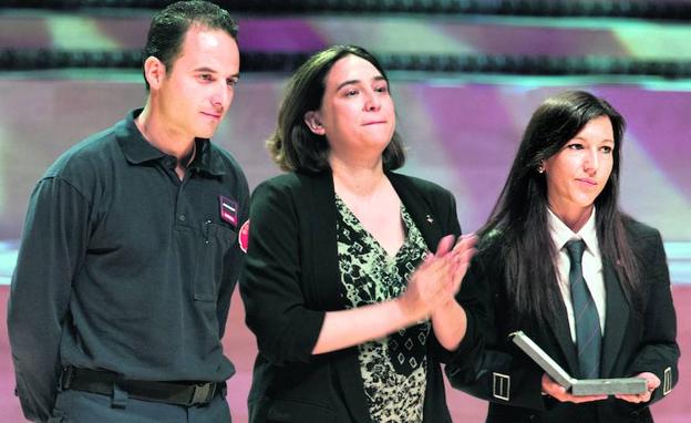 -La alcaldesa de Barcelona, Ada Colau, en el centro, emocionada junto a dos bomberos durante el acto de entrega de la Medalla de Oro en el Ayuntamiento de Barcelona 