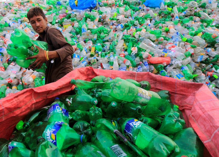 Operarios se abren paso entre montañas de botellas en una de las plantas de reciclaje de la capital de Pakistán