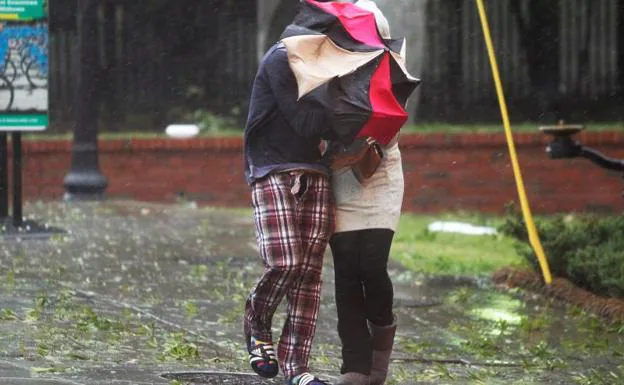 Dos personas caminan bajo el temporal.