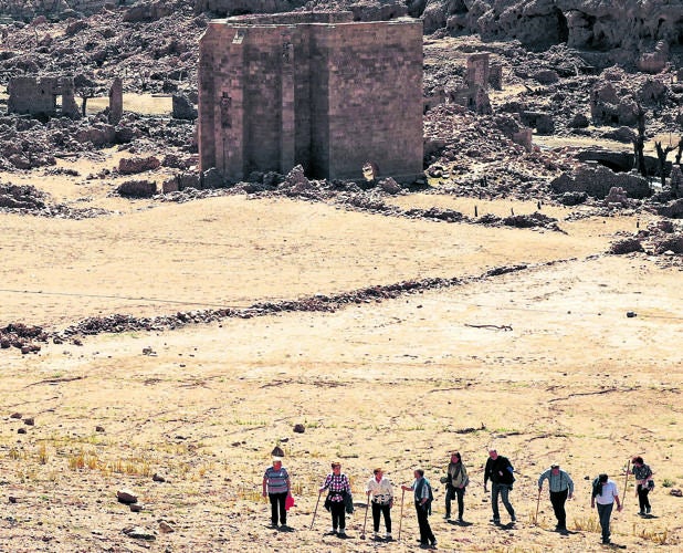 Vacío. Un grupo asciende por la ladera seca del pantano que cubre el viejo Mansilla de la Sierra, en La Rioja. Al fondo, la imponente iglesia ahora al descubierto. JUSTO RODRÍGUEZ