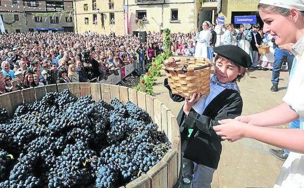 Un niño se dispone a depositar en la cuba las uvas que luego fueron pisadas para obtener el primer mosto ayer en Yécora.