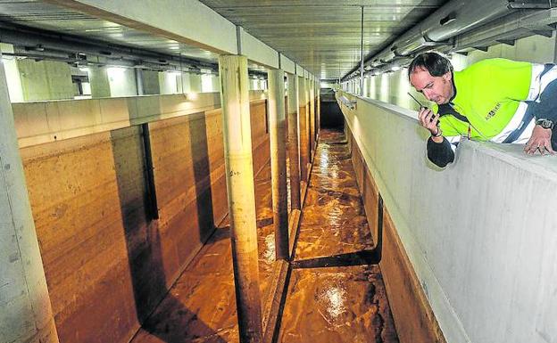 Un operario supervisa la limpieza del fondo del tanque de tormentas de Etxebarri con la salida en tromba de 50 metros cúbicos de agua.