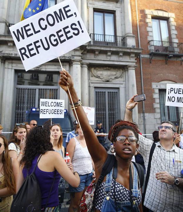 Una mujer da la bienvenida a los refugiados con una pancarta en Madrid.