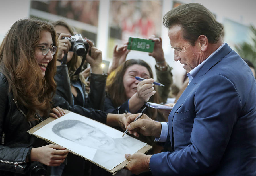 El actor Arnold Schwarzenegger firma una caricatura de él mismo a una fan en San Sebastián.