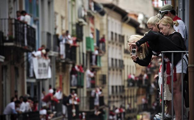 Turistas sacan fotos del encierro desde un balcón.