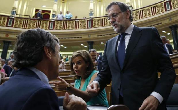 Mariano Rajoy conversa con el portavoz parlamentario del PP, Rafael Hernando, en presencia de la vicepresidenta, Soraya Sáenz de Santamaría.