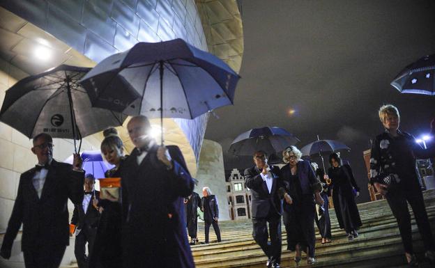 Varios invitados se protegen de la lluvia en la escalinata principal. 