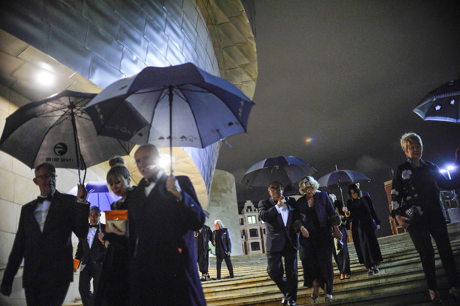 Varios invitados se protegen de la lluvia en la escalinata principal. 