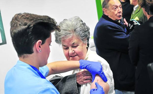 Una enfermera pone la vacuna de la gripe a una mujer mayor en Bilbao.