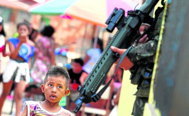 Un niño indígena observa el arma de un soldado brasileño desplegado en las maniobras militares en Tabatinga.