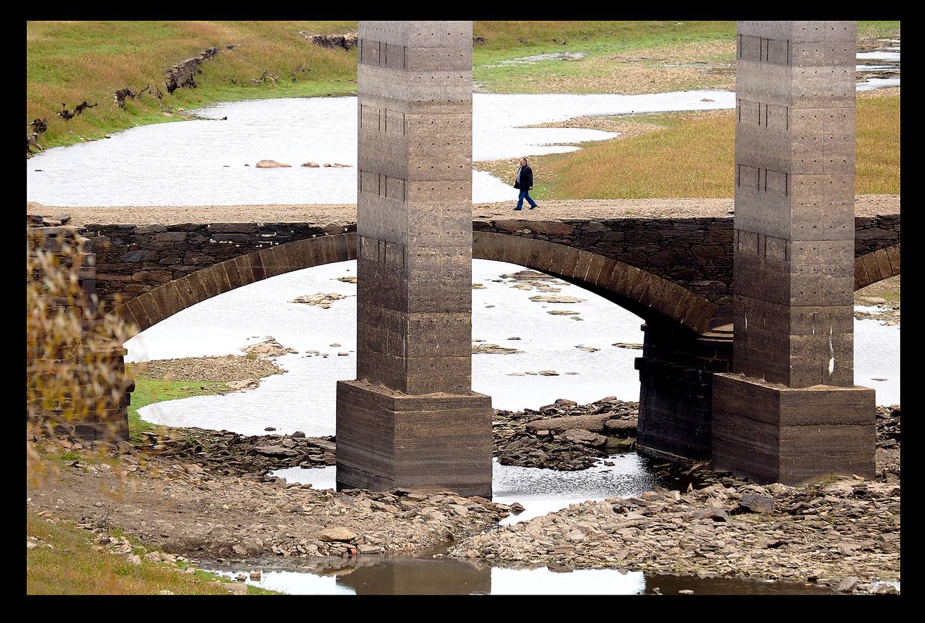 Un hombre atraviesa el antiguo puente romano que cruzaba el río Miño en el embalse de Belesar. El Miño es el río más grande de Galicia, ya su paso por Lugo, la reserva hidráulica se encuentra al 37% de su capacidad total, un registro solo superado a peor durante el periodo de sequí­a comprendido entre 1992 y 1995. 